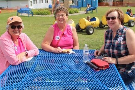 photo of three women sitting at table smiling at camera