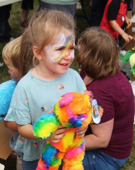 Girl with painted face holding teddy bear
